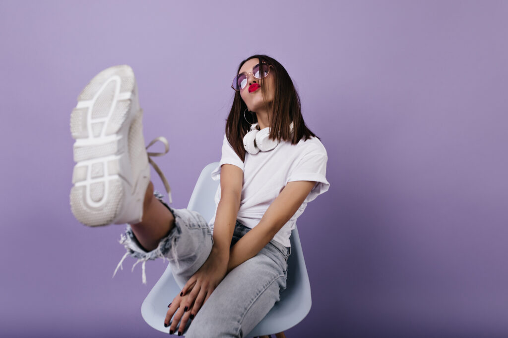 Confident european lady in white sneakers sitting on chair and m