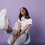 Confident european lady in white sneakers sitting on chair and m