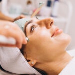 Cosmetologist applying mask on a face of client in a beauty salon