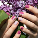 Pink nail design. Female hand with pink manicure holding purple lilac.