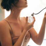 attractive seductive sensual stylish woman in boho dress sitting vintage retro cafe holding perfume