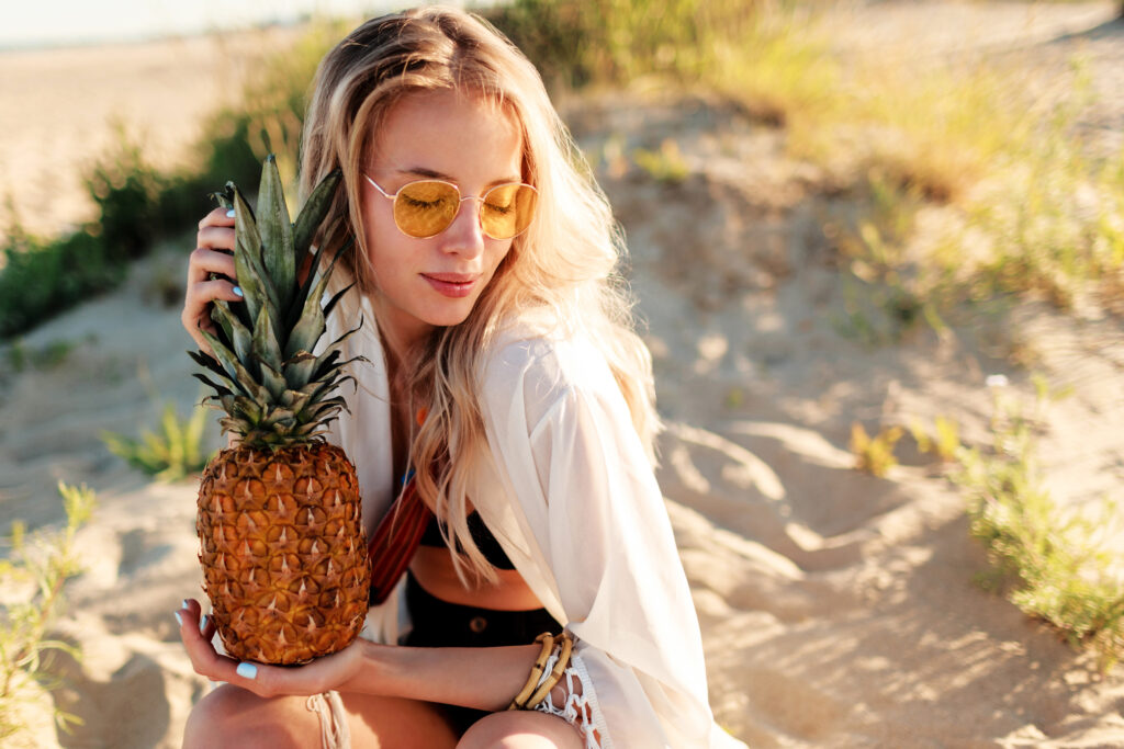lifestyle-outdoor-picture-laughing-pretty-woman-with-juicy-pineapple-relaxing-sunny-beach-trendy-summer-outfit