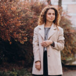 Pretty woman with curly hair walking in an autumn coat