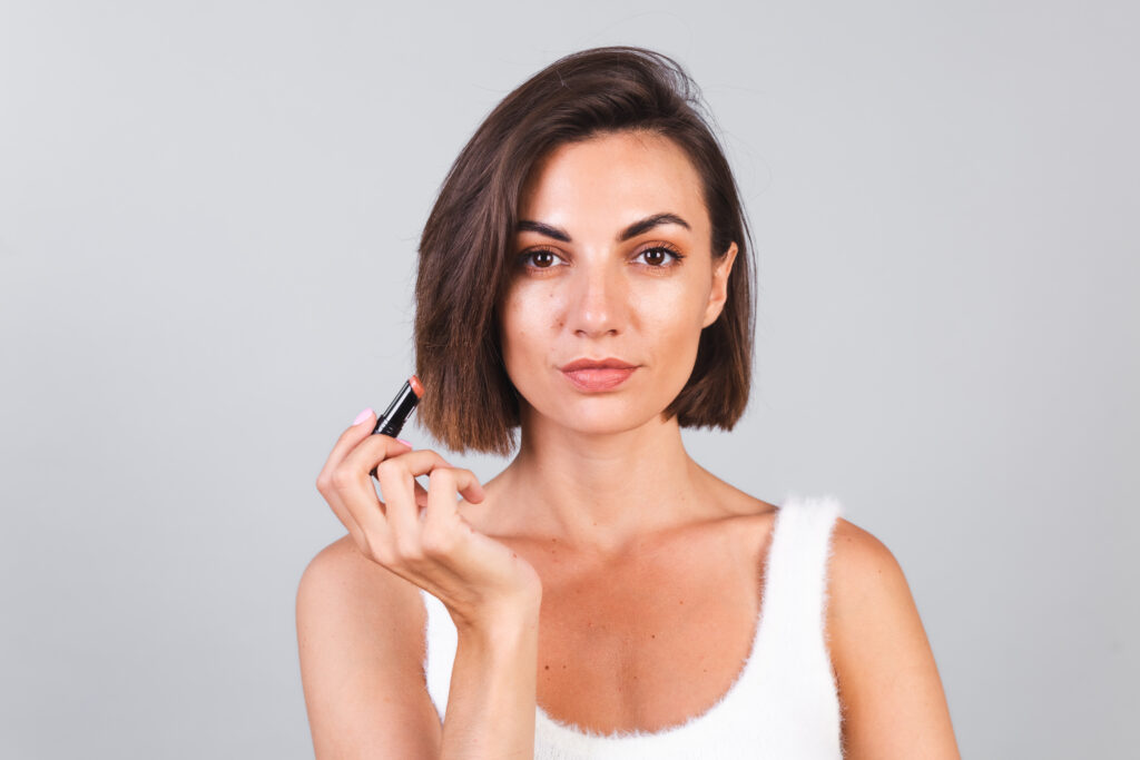 Close beauty portrait of woman with makeup and brown lipstick on gray background